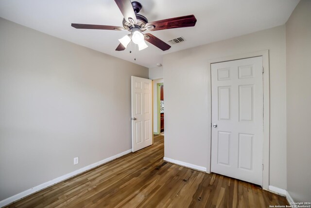 unfurnished bedroom featuring ceiling fan and dark hardwood / wood-style floors