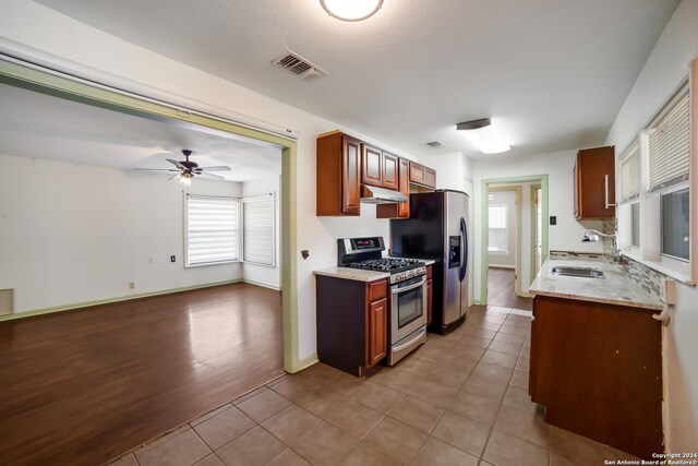 kitchen featuring ceiling fan, light stone counters, light tile patterned floors, sink, and stainless steel appliances