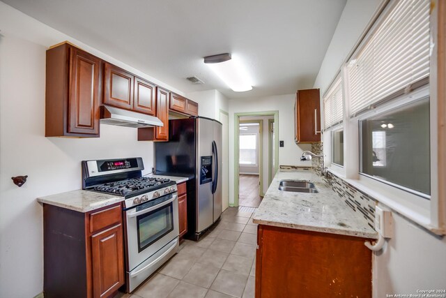 kitchen featuring light tile patterned flooring, appliances with stainless steel finishes, sink, and light stone counters