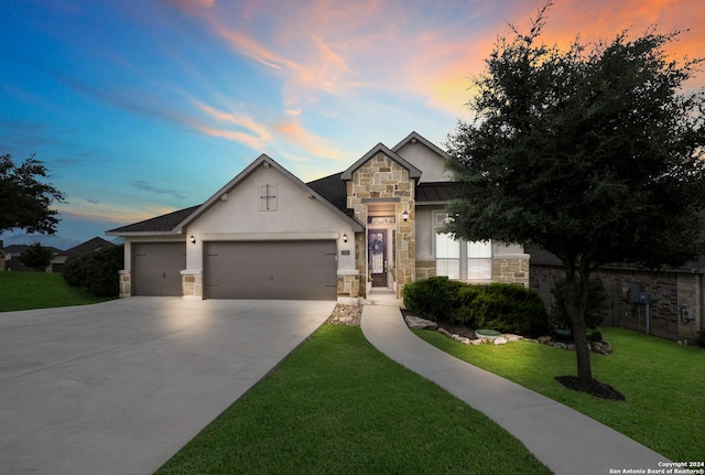 view of front of home featuring stucco siding, a front yard, a standing seam roof, a garage, and stone siding