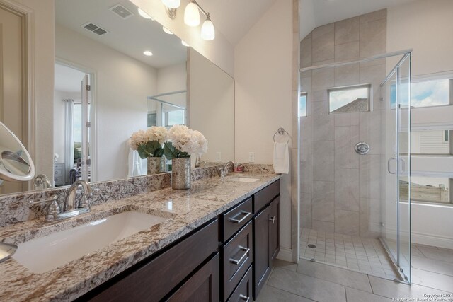 bathroom with tile patterned flooring, vanity, and walk in shower