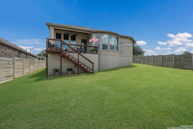 rear view of property with ceiling fan and a lawn