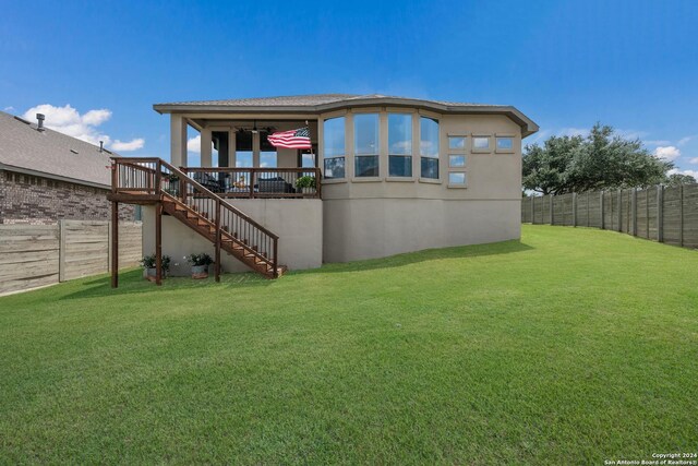 back of house with ceiling fan and a yard