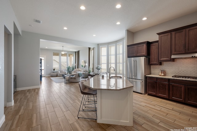 kitchen featuring appliances with stainless steel finishes, an island with sink, a wealth of natural light, and tasteful backsplash