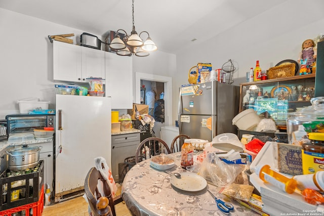 kitchen with light wood-type flooring, white cabinets, white fridge, a notable chandelier, and stainless steel fridge