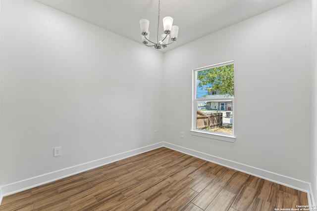 spare room featuring hardwood / wood-style flooring and a chandelier