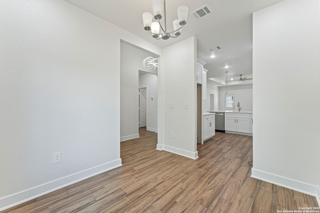 unfurnished dining area with hardwood / wood-style floors, sink, and a notable chandelier