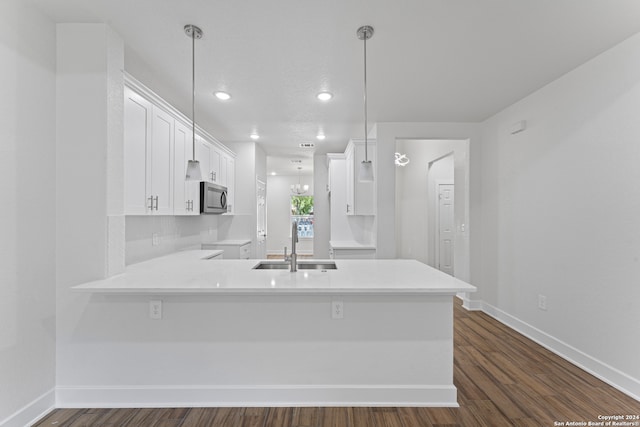 kitchen with white cabinets, decorative light fixtures, kitchen peninsula, and dark hardwood / wood-style floors