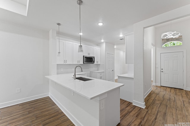 kitchen featuring sink, dark hardwood / wood-style floors, white cabinetry, hanging light fixtures, and kitchen peninsula