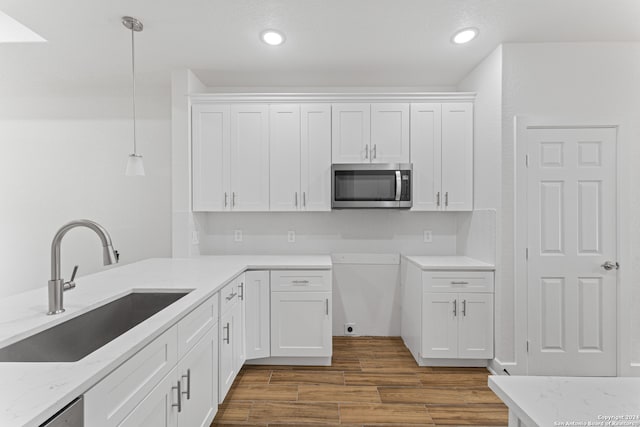 kitchen featuring sink, decorative light fixtures, hardwood / wood-style flooring, white cabinetry, and stainless steel appliances