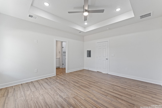 spare room featuring ceiling fan, a tray ceiling, and light hardwood / wood-style floors