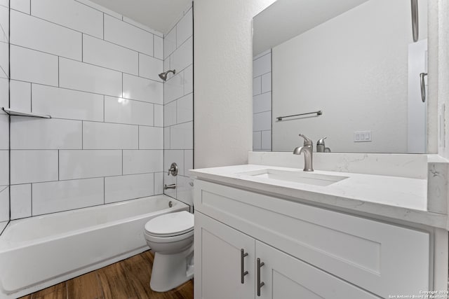 full bathroom featuring hardwood / wood-style floors, tiled shower / bath combo, toilet, and vanity