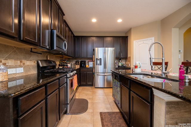 kitchen with dark stone countertops, backsplash, stainless steel appliances, dark brown cabinets, and sink