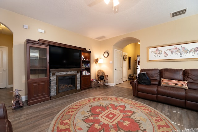 living room with a fireplace, dark hardwood / wood-style flooring, and ceiling fan