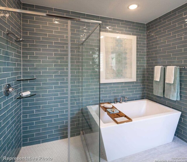 bathroom with tile walls and independent shower and bath