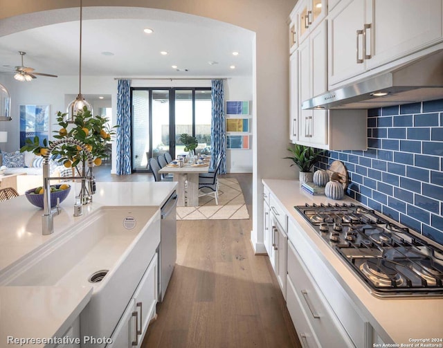 kitchen featuring pendant lighting, tasteful backsplash, hardwood / wood-style floors, white cabinets, and appliances with stainless steel finishes