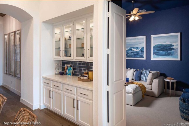 bar featuring dark hardwood / wood-style flooring, white cabinets, backsplash, and ceiling fan