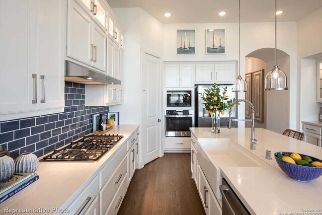 kitchen with stainless steel appliances, white cabinetry, tasteful backsplash, pendant lighting, and dark hardwood / wood-style flooring