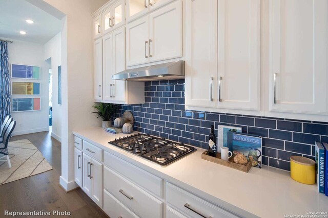 kitchen with dark wood-type flooring, tasteful backsplash, stainless steel gas cooktop, and white cabinets