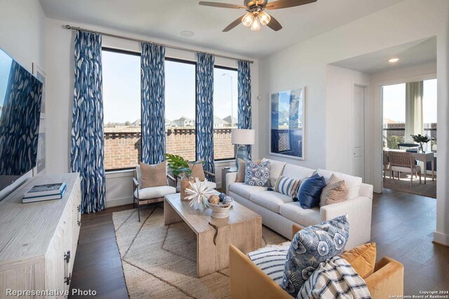 living room with a wealth of natural light, ceiling fan, and dark wood-type flooring