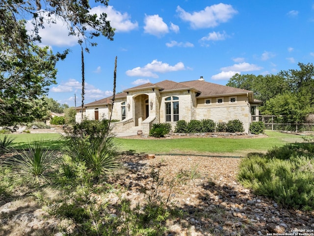 mediterranean / spanish house with stone siding and a front lawn