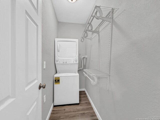 clothes washing area featuring stacked washer / drying machine and dark hardwood / wood-style floors