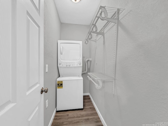 walk in closet with dark wood-type flooring and stacked washing maching and dryer