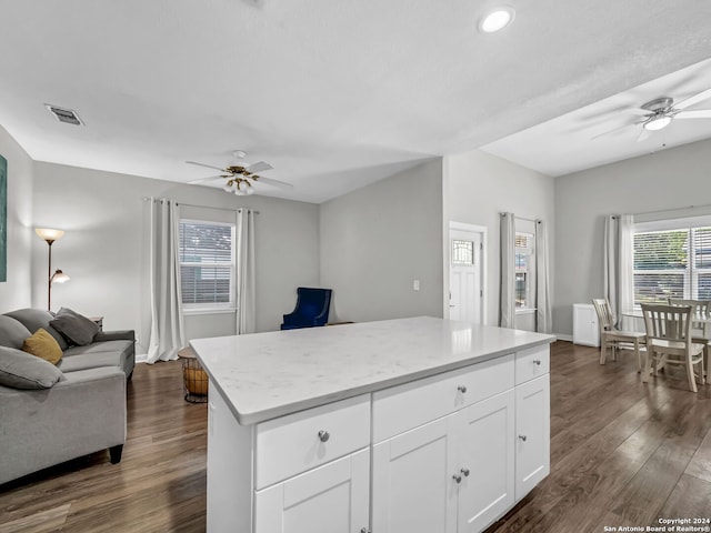 kitchen featuring a center island, white cabinetry, light stone counters, dark hardwood / wood-style floors, and ceiling fan