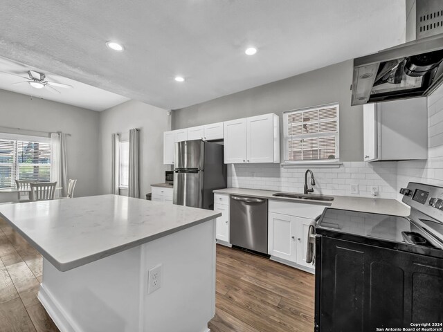 kitchen with ceiling fan, white cabinets, appliances with stainless steel finishes, hardwood / wood-style flooring, and a center island