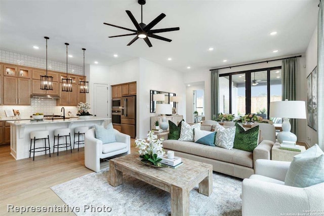 living room with ceiling fan, light wood-type flooring, and sink