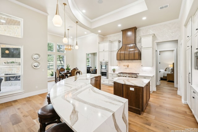 kitchen featuring white cabinets, premium range hood, hanging light fixtures, and a large island