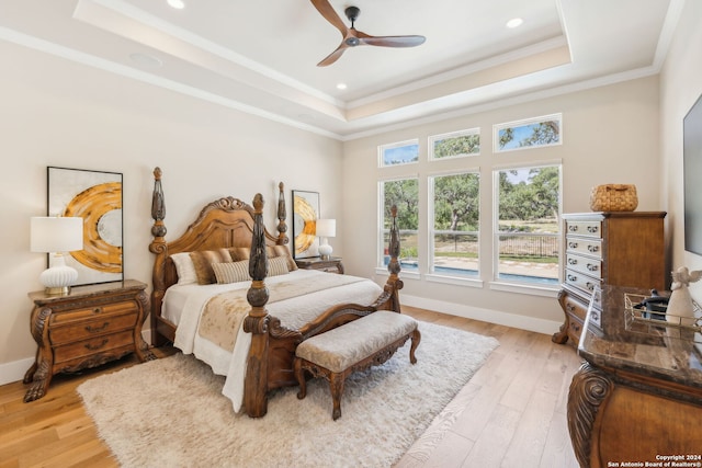 bedroom featuring ornamental molding, a raised ceiling, and light wood-style flooring