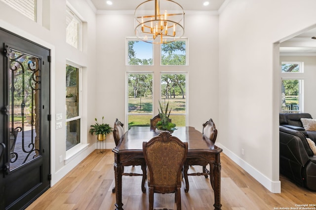 dining area with ornamental molding, light wood-type flooring, a high ceiling, and baseboards