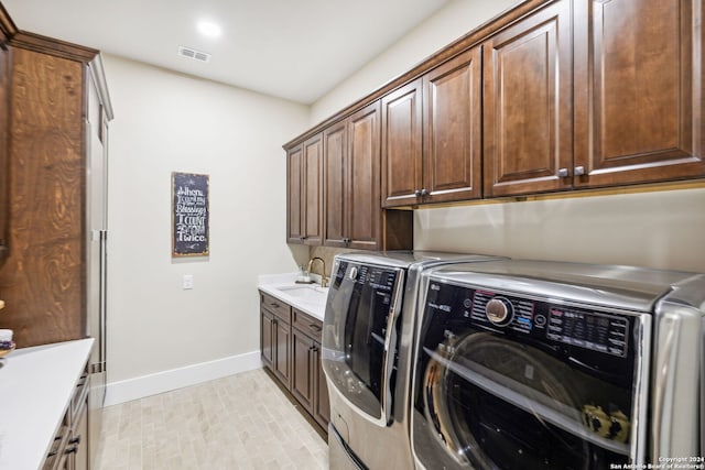 clothes washing area with cabinet space, baseboards, visible vents, separate washer and dryer, and a sink