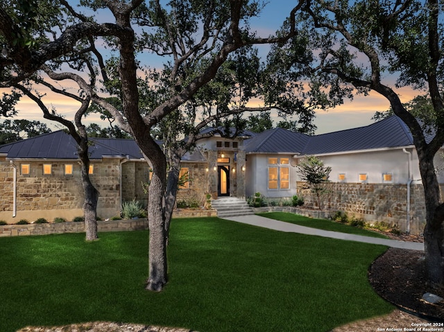 view of front of house with stone siding, a standing seam roof, metal roof, and a yard