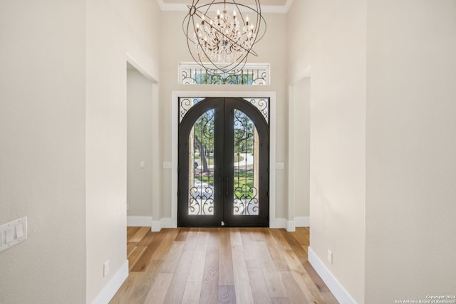 entryway with ornamental molding, light wood-type flooring, french doors, and baseboards