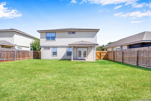 rear view of property with french doors, a lawn, and a fenced backyard