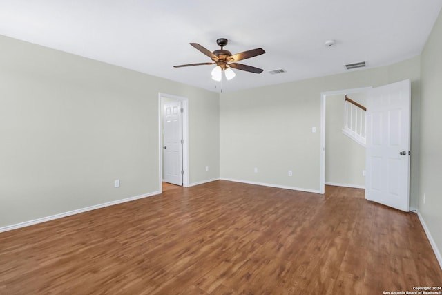 spare room with wood finished floors, visible vents, and baseboards