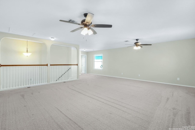 unfurnished room with carpet floors, attic access, baseboards, and ceiling fan