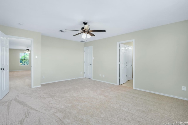 unfurnished room featuring light colored carpet, visible vents, ceiling fan, and baseboards