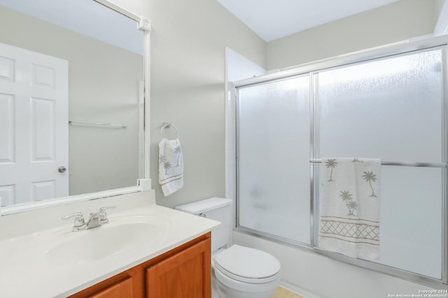 bathroom with toilet, bath / shower combo with glass door, and vanity