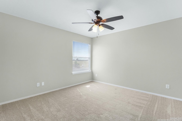 empty room with light carpet, a ceiling fan, and baseboards