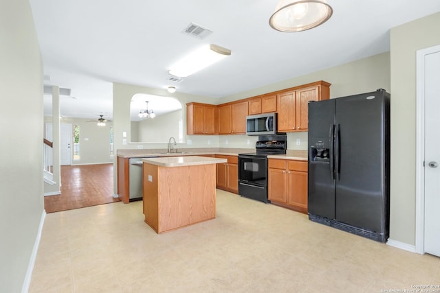 kitchen with brown cabinets, a center island, light countertops, black appliances, and a sink