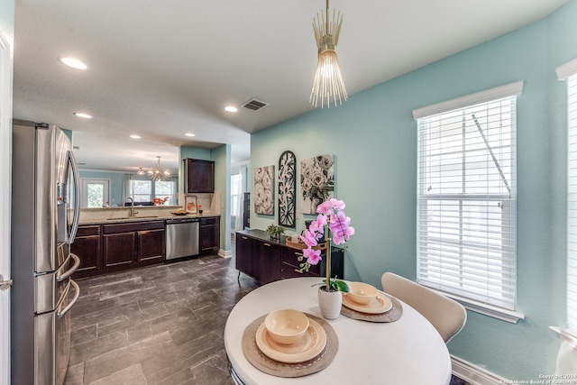 dining area featuring sink, a notable chandelier, plenty of natural light, and dark tile patterned flooring