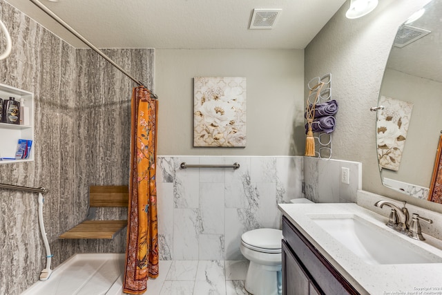 bathroom with a shower with shower curtain, toilet, vanity, tile patterned floors, and tile walls