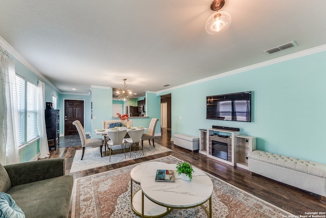 living room with dark hardwood / wood-style flooring, an inviting chandelier, and crown molding