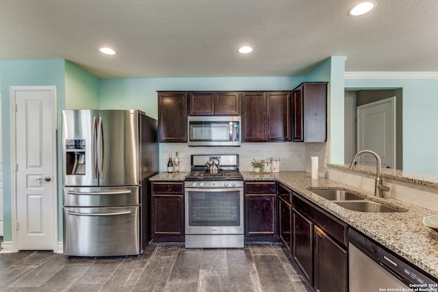 kitchen featuring stainless steel appliances, tasteful backsplash, sink, light stone counters, and a textured ceiling