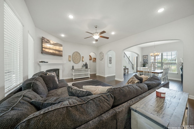 living room featuring ceiling fan with notable chandelier and dark hardwood / wood-style floors