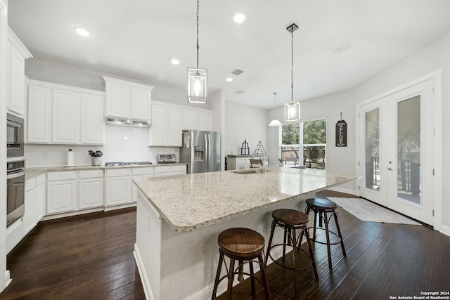 kitchen with appliances with stainless steel finishes, dark wood-type flooring, white cabinets, and backsplash