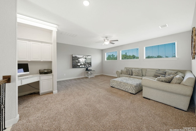 carpeted living room featuring ceiling fan and built in desk